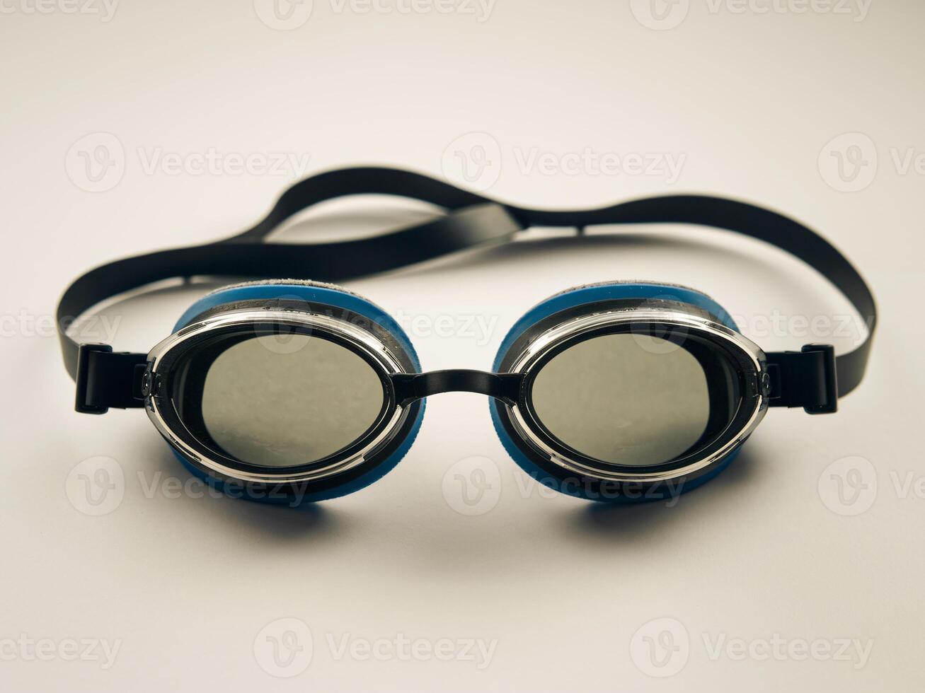 Black and blue swimming goggles on a light background, ready for a swim. photo