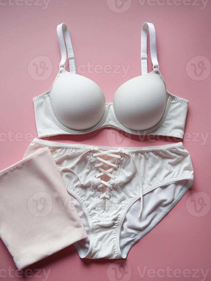Elegant white lingerie set displayed on a soft pink background, perfect for a romantic mood. photo