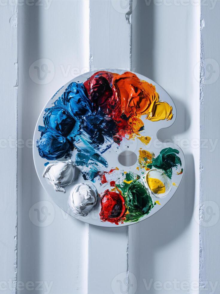 A vibrant artist's palette displaying an array of colorful paints on a white wooden background. photo