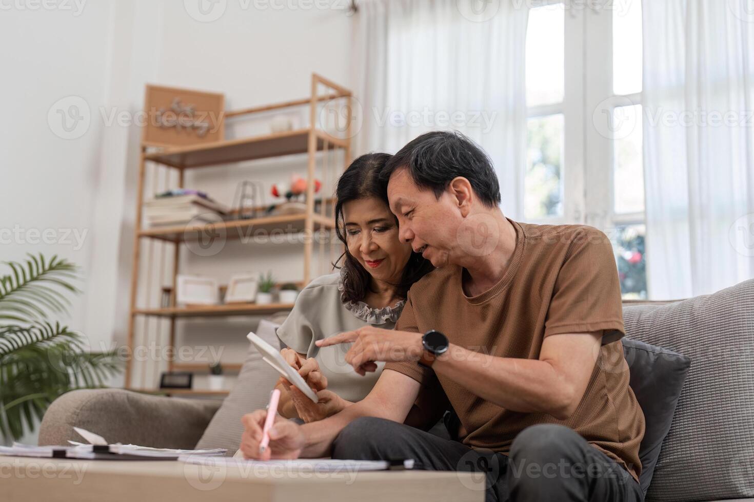Elderly Couple Engaged in Financial Planning at Home with Documents and Calculator on Table photo