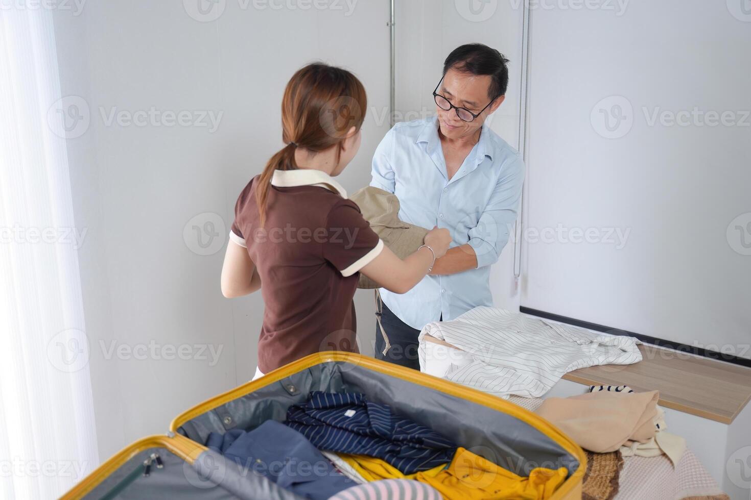 Father and Daughter Bonding While Folding Clothes and Packing a Suitcase for a Family Trip at Home photo