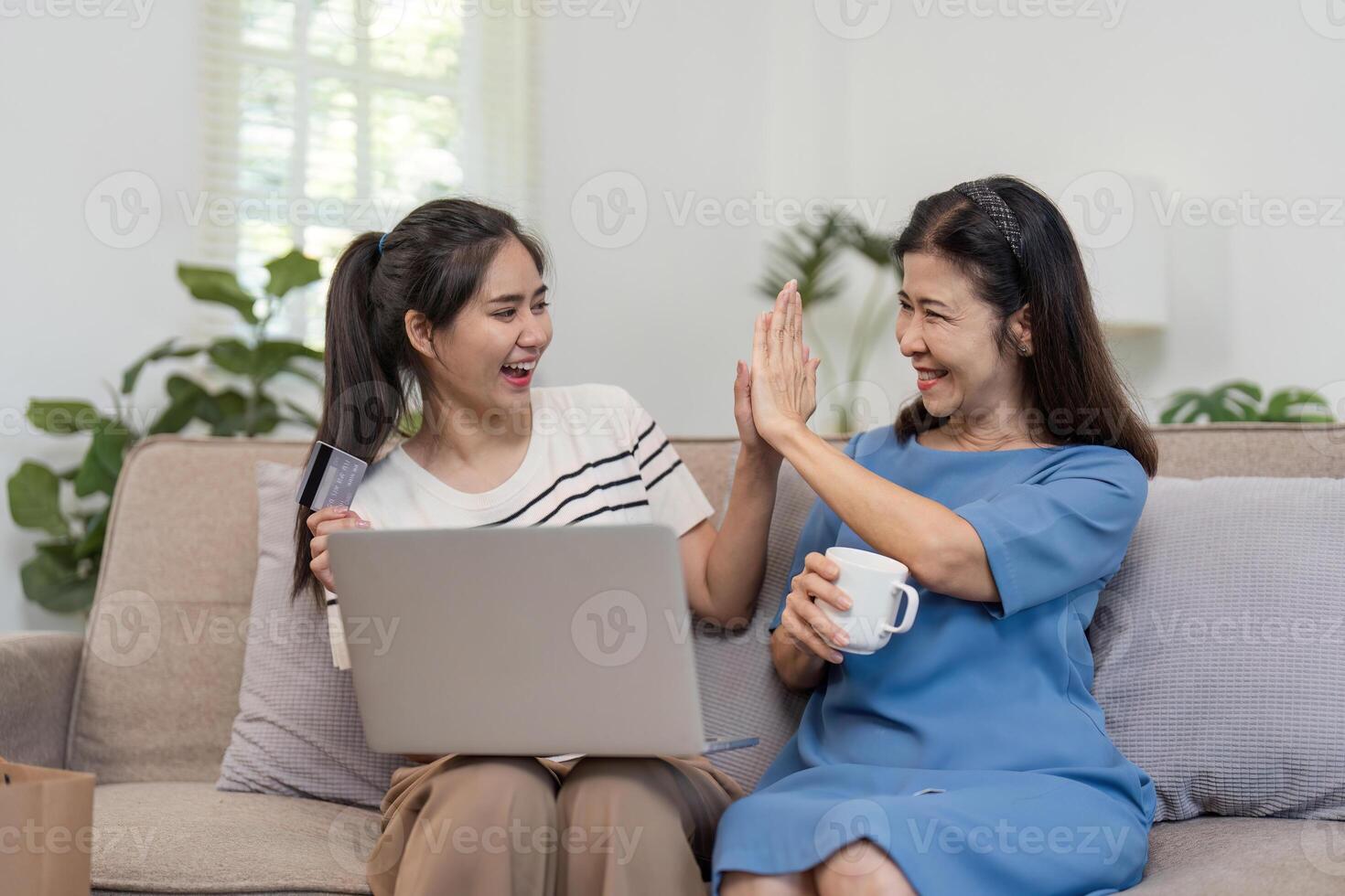 Mother and Child Enjoying Online Shopping Together with Credit Card and Laptop in Cozy Home Setting photo