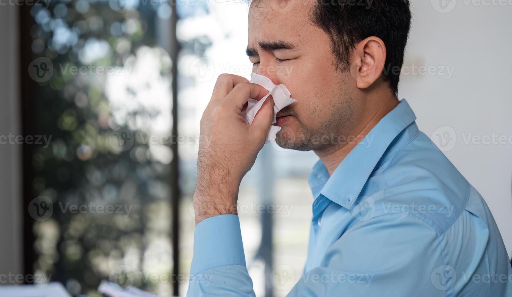 Office Worker Feeling Unwell with Cold Symptoms at Desk in Modern Workplace Environment photo