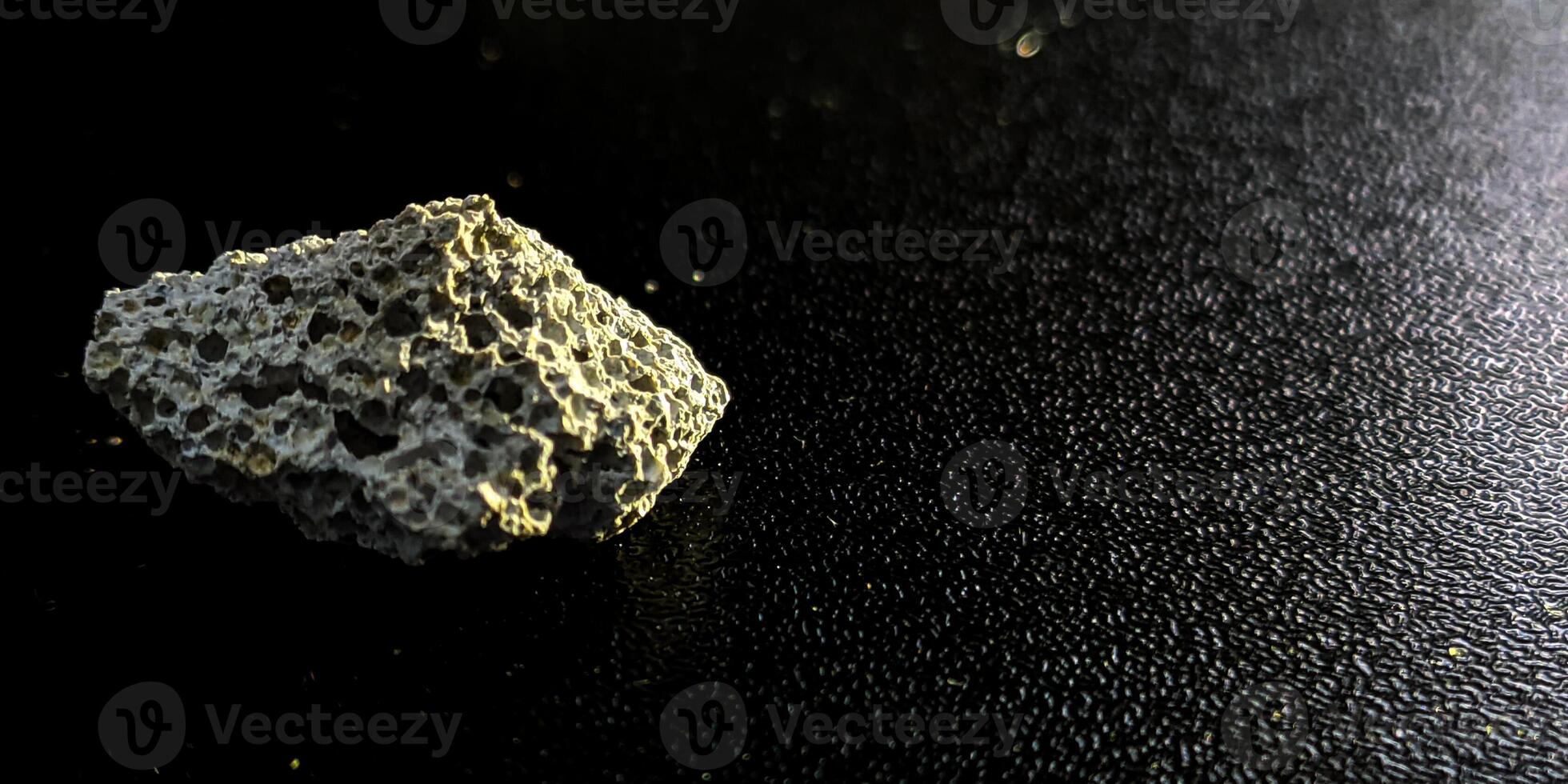 a rock sitting on a black surface photo