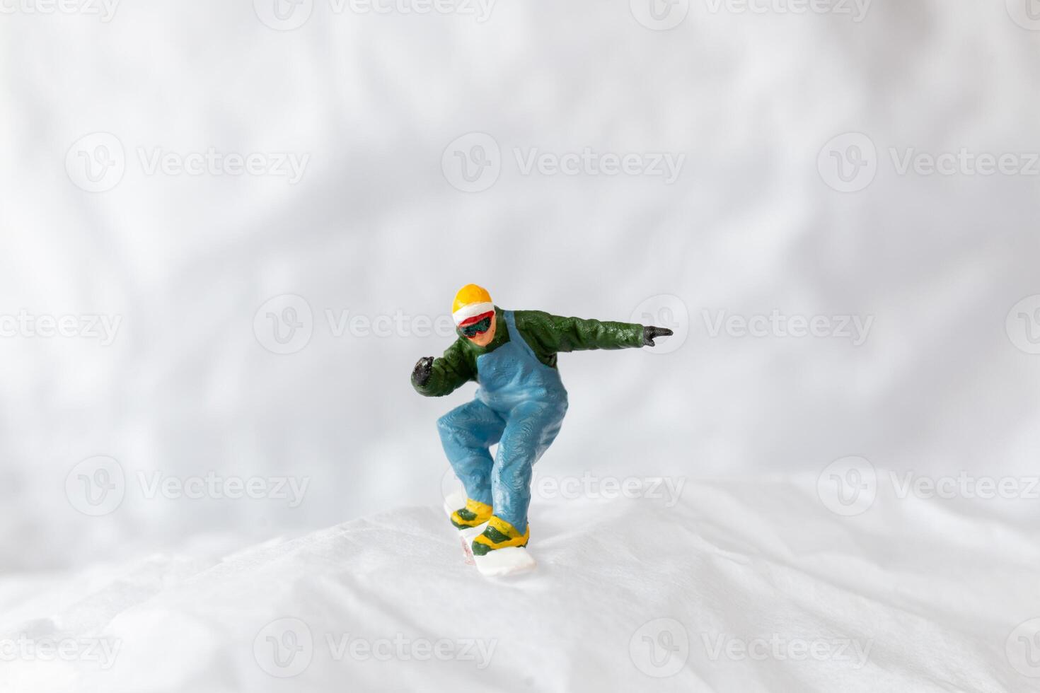 Miniature people snowboarder dressed in vibrant winter gear, carving through a snowy slope photo