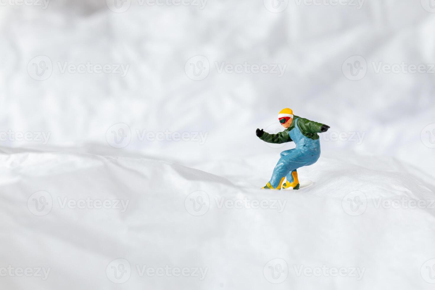 Miniature people snowboarder dressed in vibrant winter gear, carving through a snowy slope photo