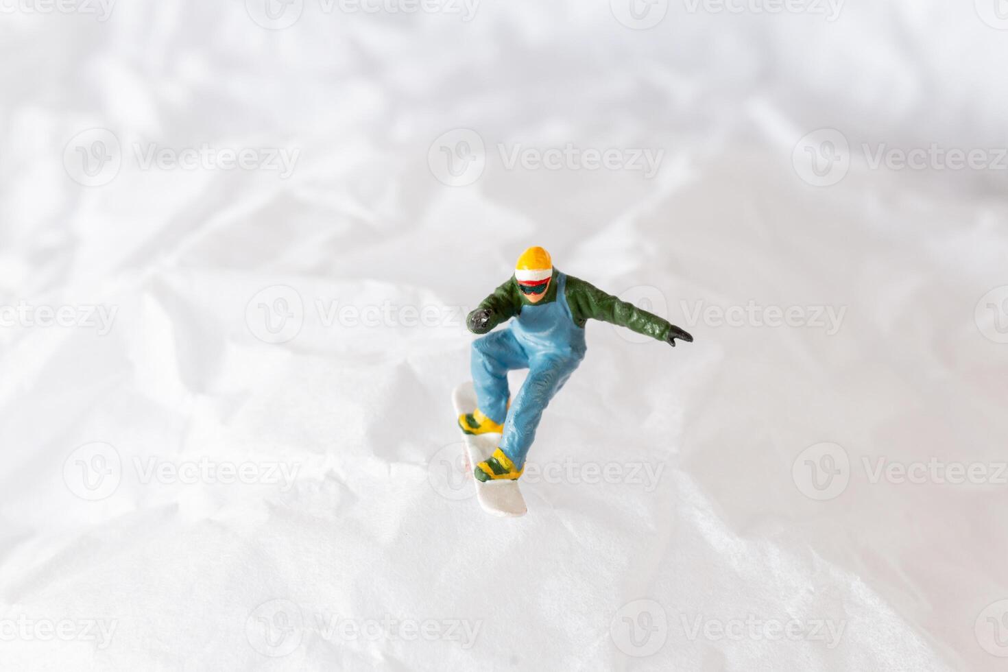 Miniature people snowboarder dressed in vibrant winter gear, carving through a snowy slope photo