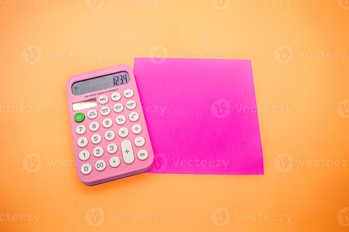 A pink calculator displaying the number 1234 is placed next to a bright pink square paper on an orange background. The vibrant colors make the image visually appealing photo