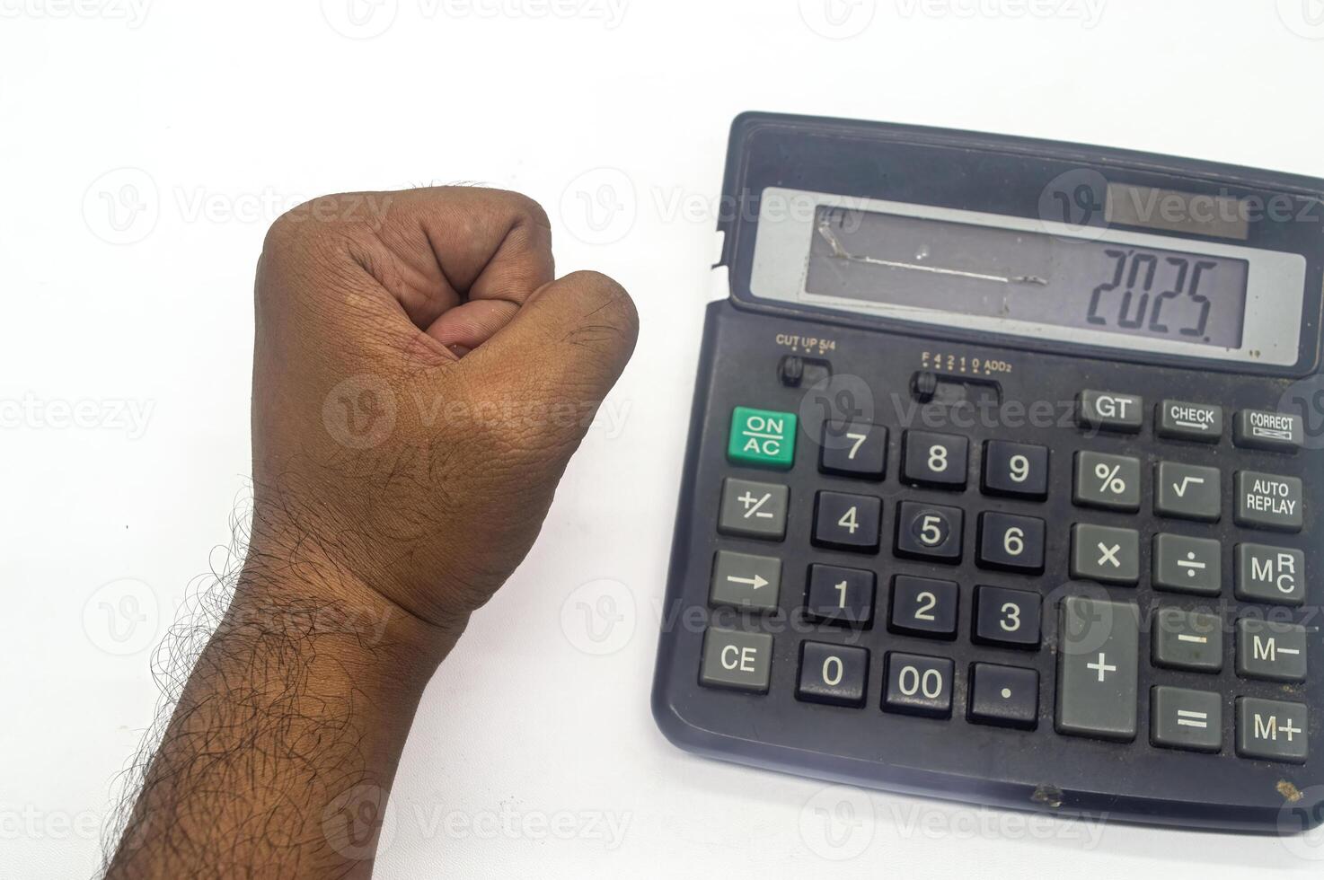 A hand forming a fist is placed next to a calculator displaying the number 2025, symbolizing financial goals or future planning photo