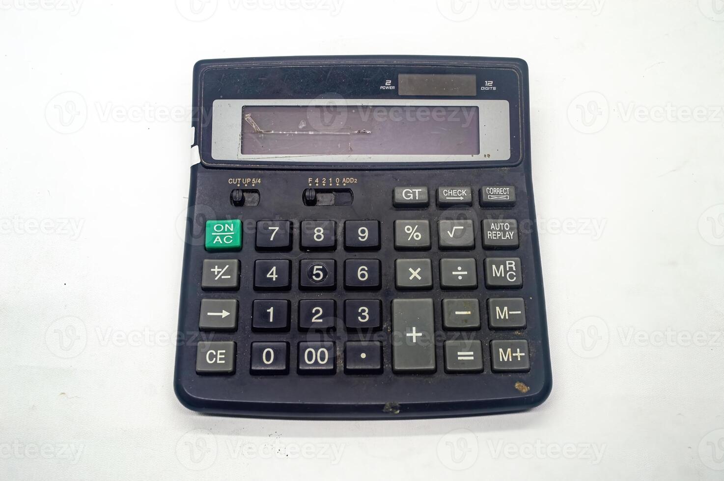 Old, worn out black calculator with a damaged display screen, showing various function buttons and numeric keys, placed on a white background photo