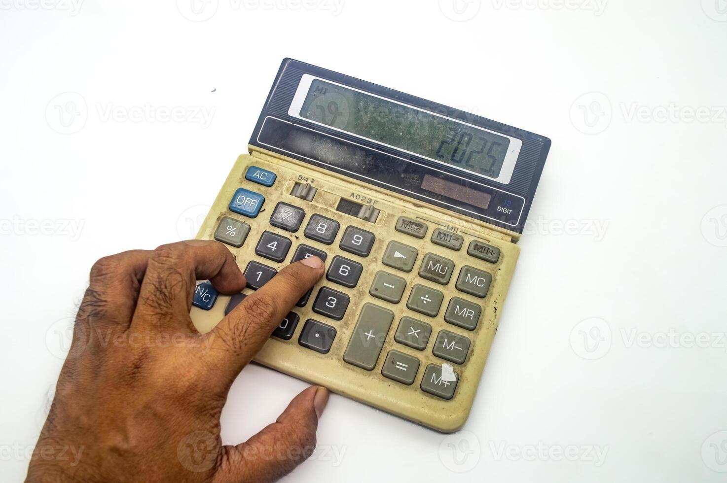 A close up of a hand pressing buttons on an old, dusty calculator displaying the number 2025. This image represents financial calculations or accounting work photo