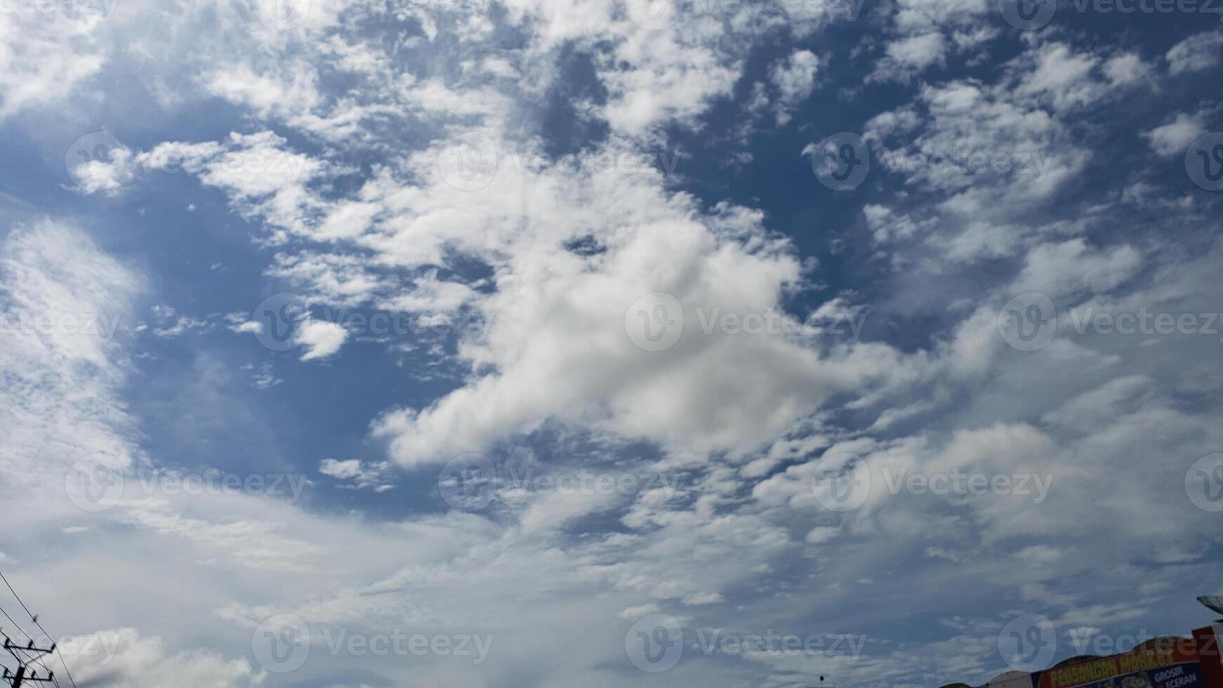 A bright blue sky with scattered fluffy clouds photo