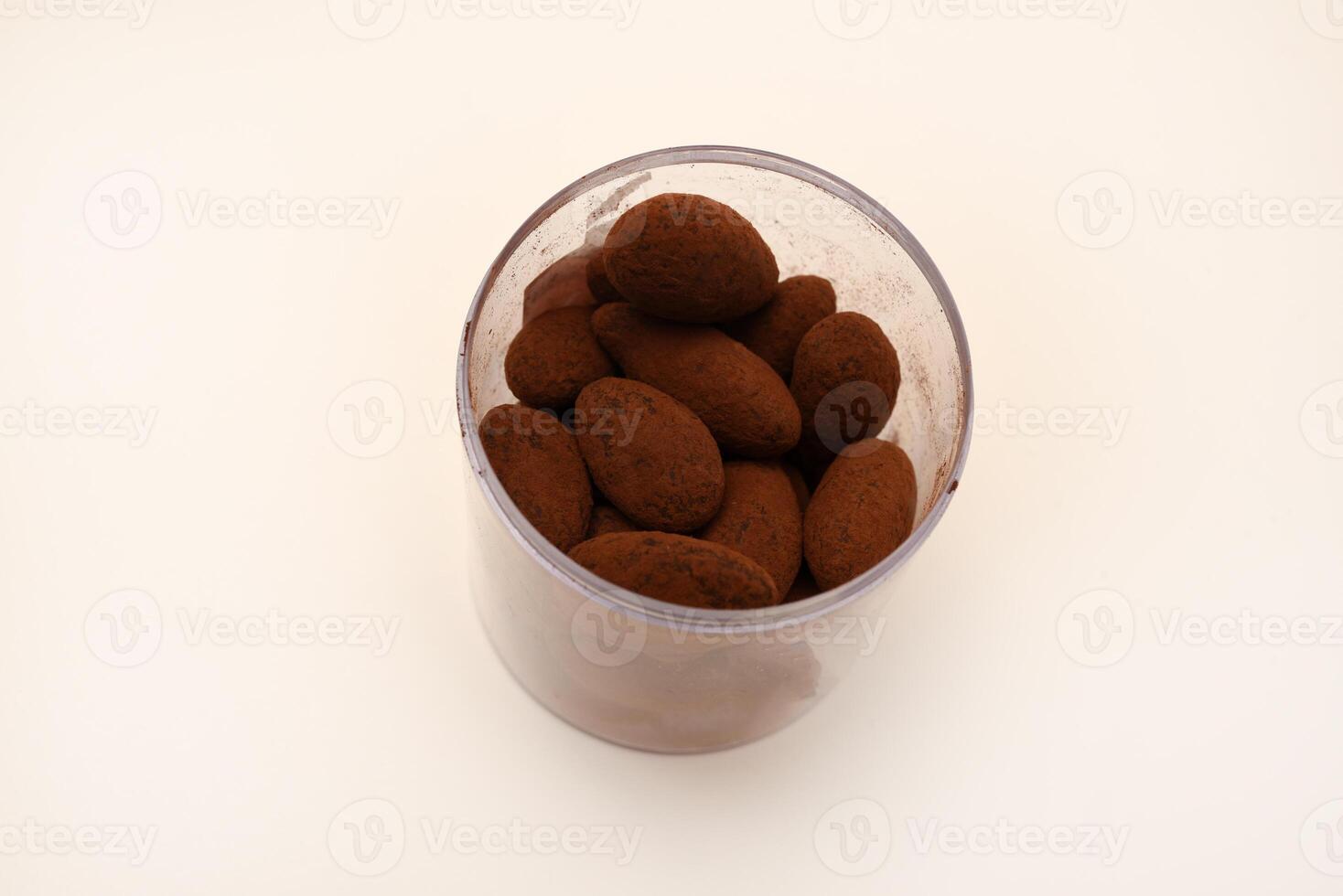Chocolate-covered almonds in a jar on a white background. photo