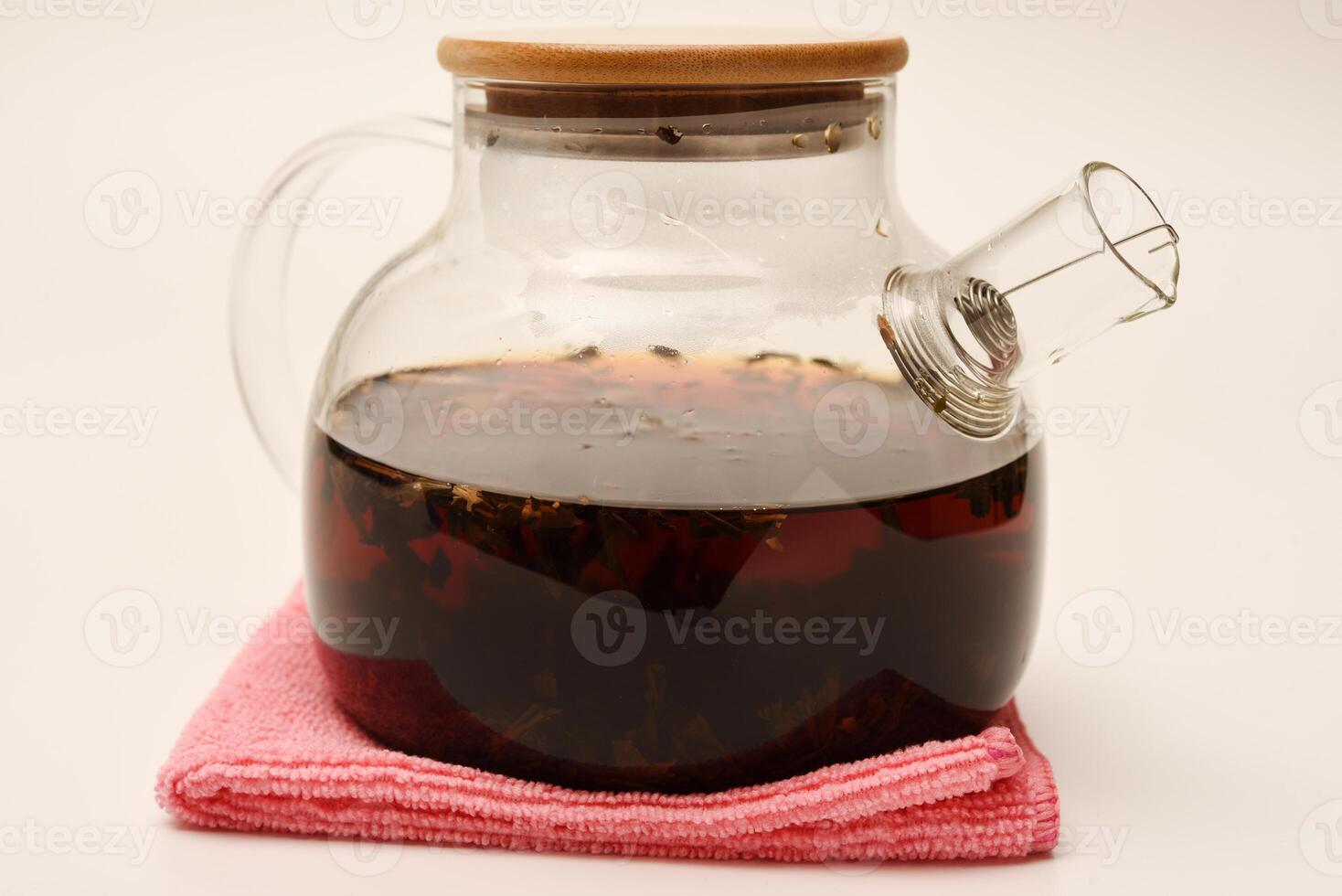 Glass teapot with wooden lid on a white background. A teapot with a teapot inside. photo