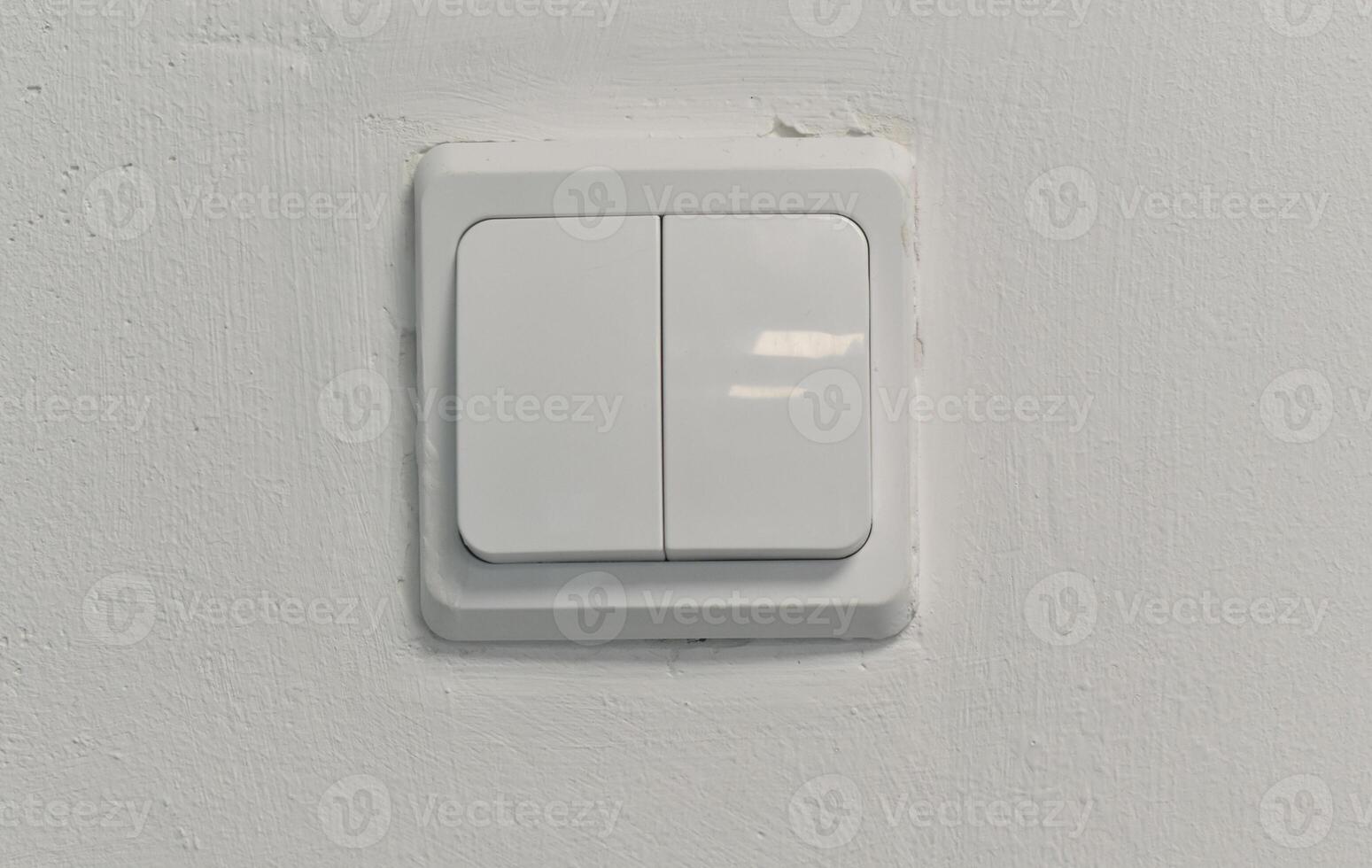 There is an electric switch on the wall. A white wall with a light switch. photo