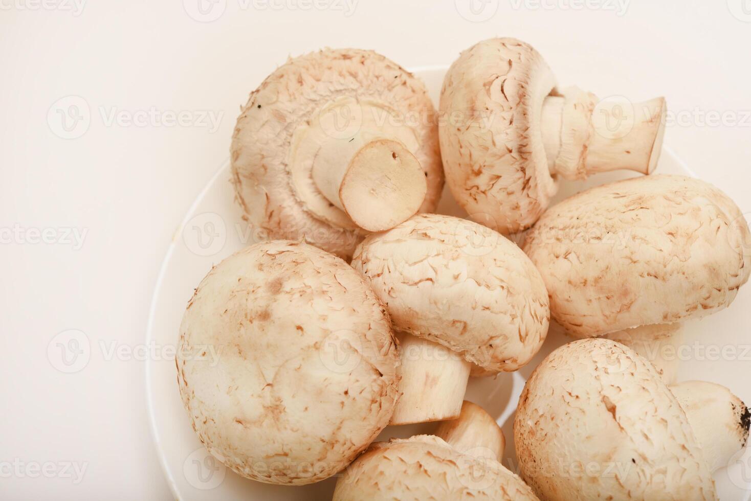 Fresh champignons on a white plate. Mushrooms on a white background. photo