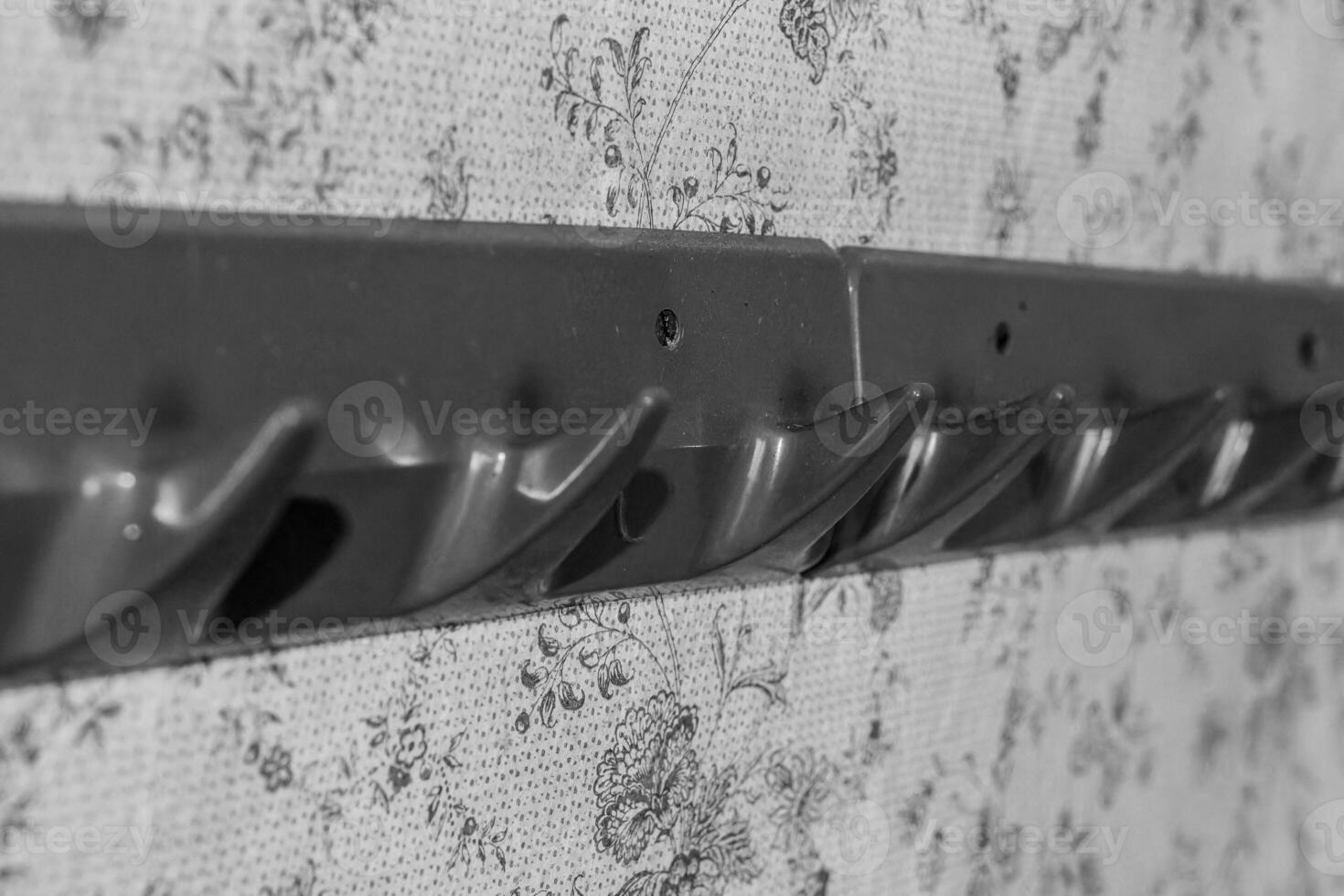 Closet organizer with hooks mounted on a floral patterned background in a home setting photo
