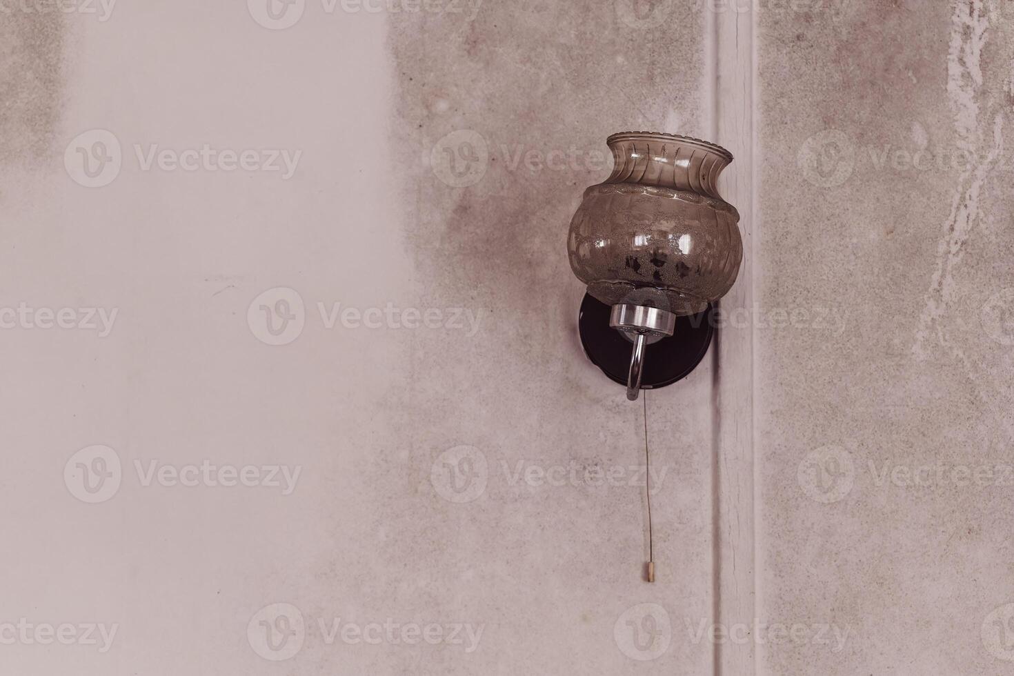 Unique vintage wall lamp hanging on a textured wall in a dimly lit room enhancing the cozy atmosphere photo