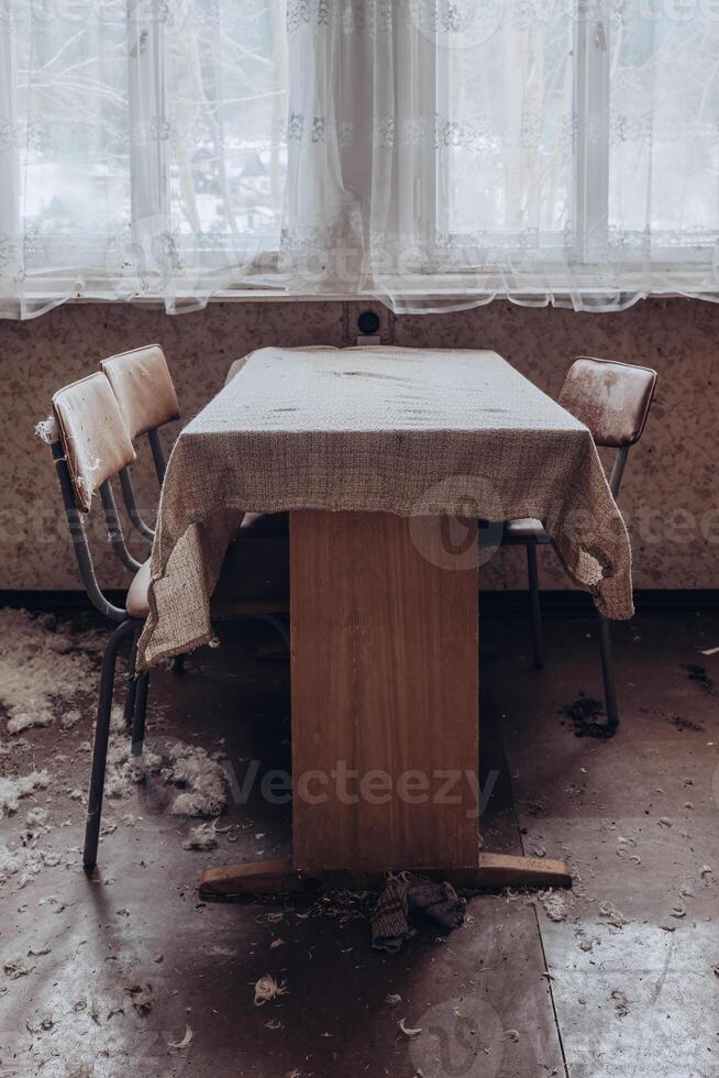 Abandoned dining area with worn-out furniture and dusty atmosphere in an old building photo