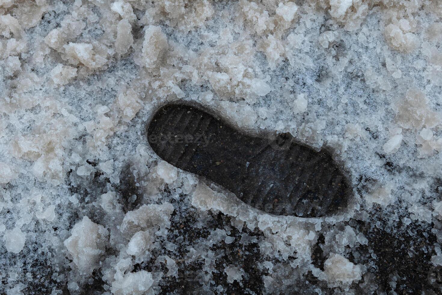 Snow-covered ground shows a single shoeprint left behind in a cold winter landscape photo
