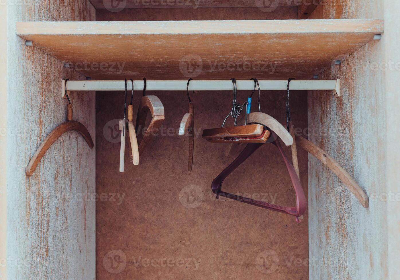 Wooden hangers hang in an empty wardrobe with some signs of wear and rustic charm showcasing their utility and design photo