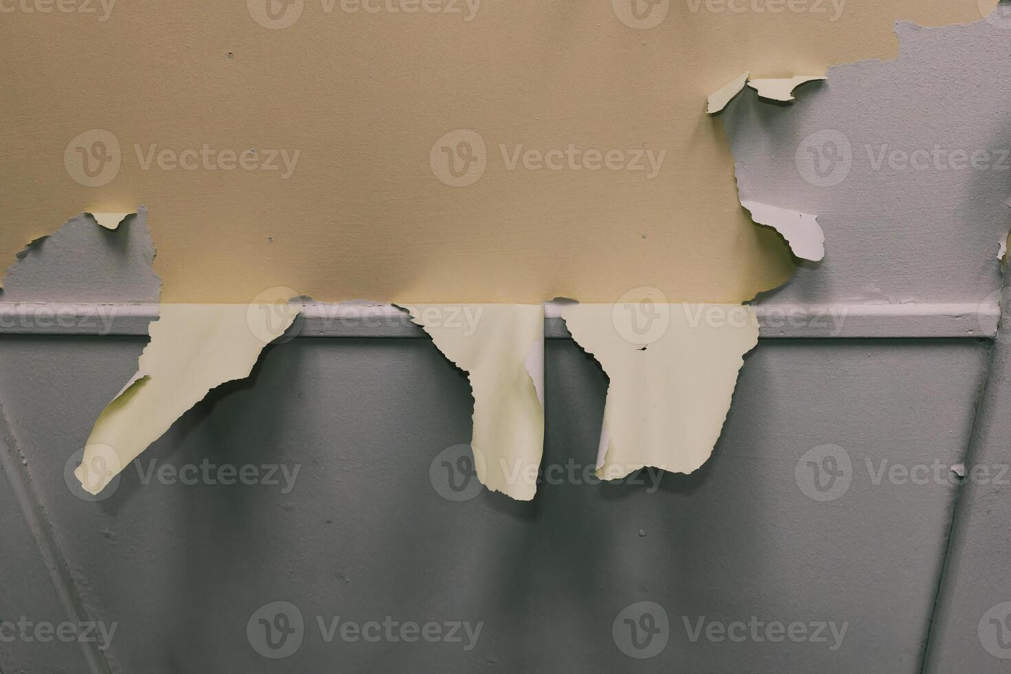 Torn wall paint revealing underlying layers in an indoor setting during daylight hours photo