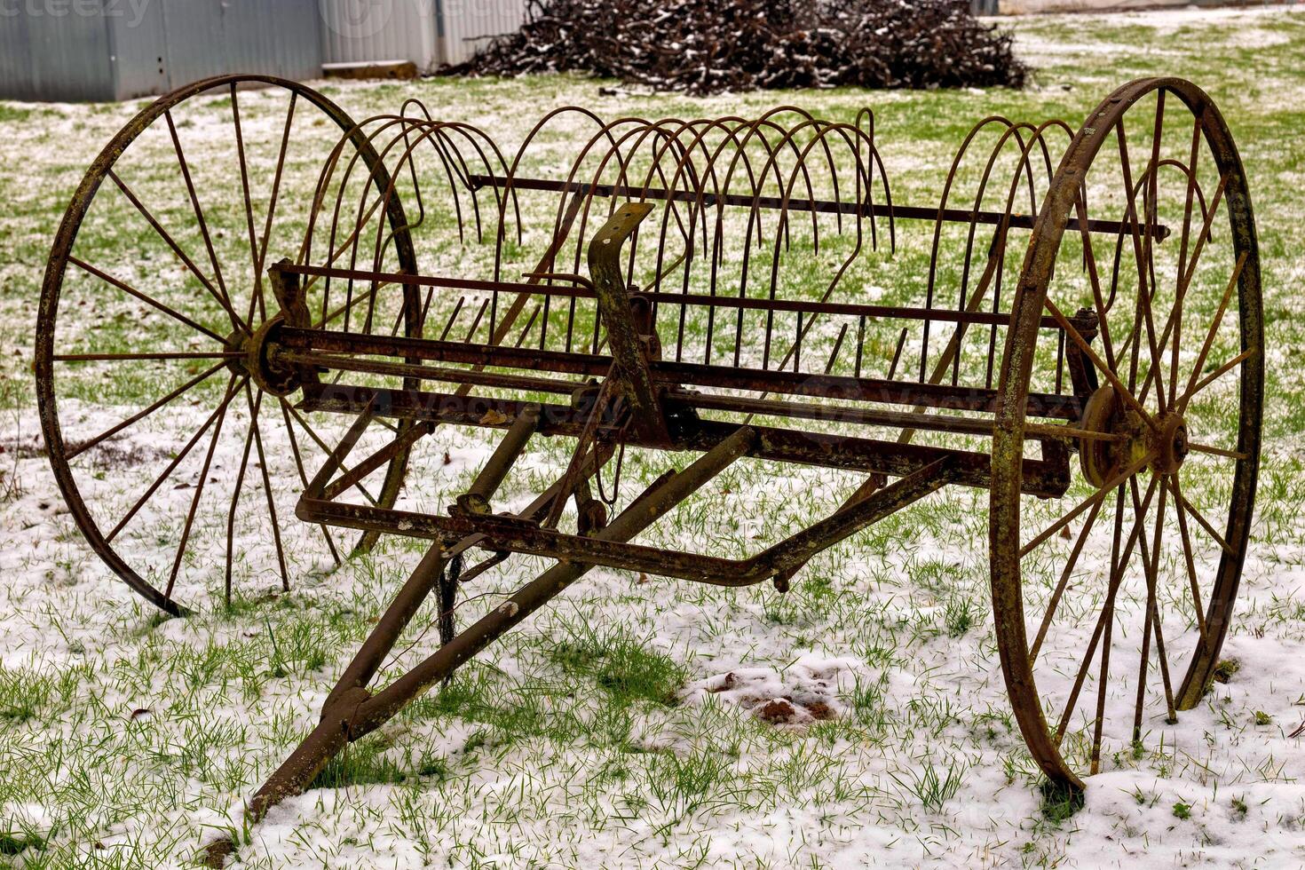 Old rusty farming equipment rests on a snowy field in a rural area during winter months photo
