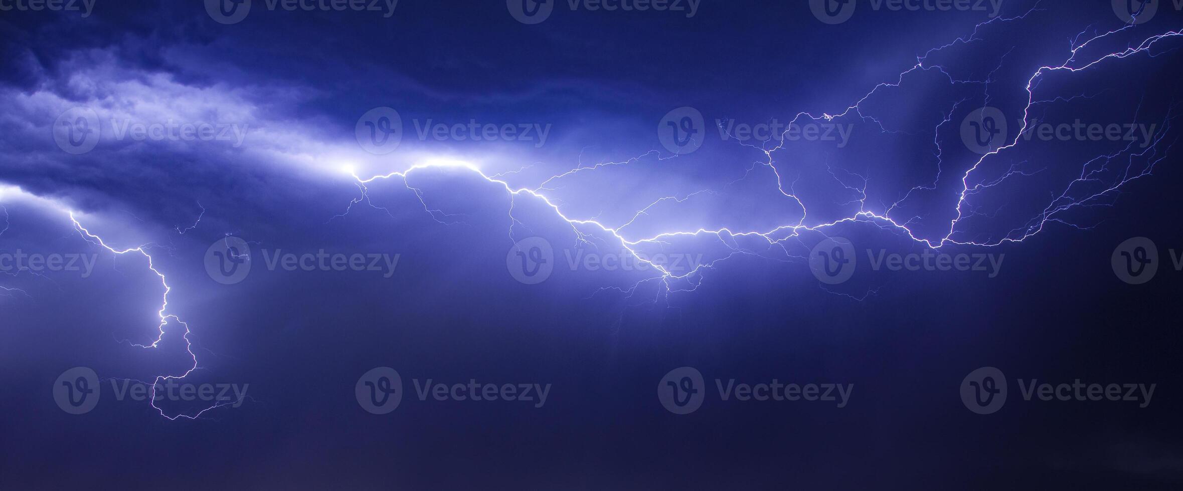 Lightning strikes over a dark sky with a large cloud in the background photo