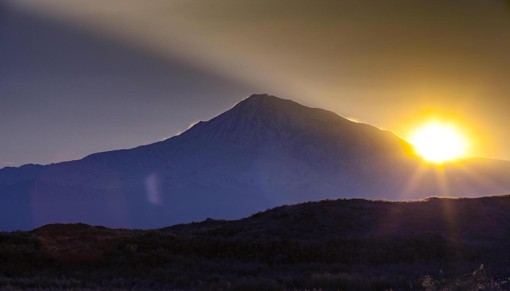 Sunset over color mountain silhouette with rays photo