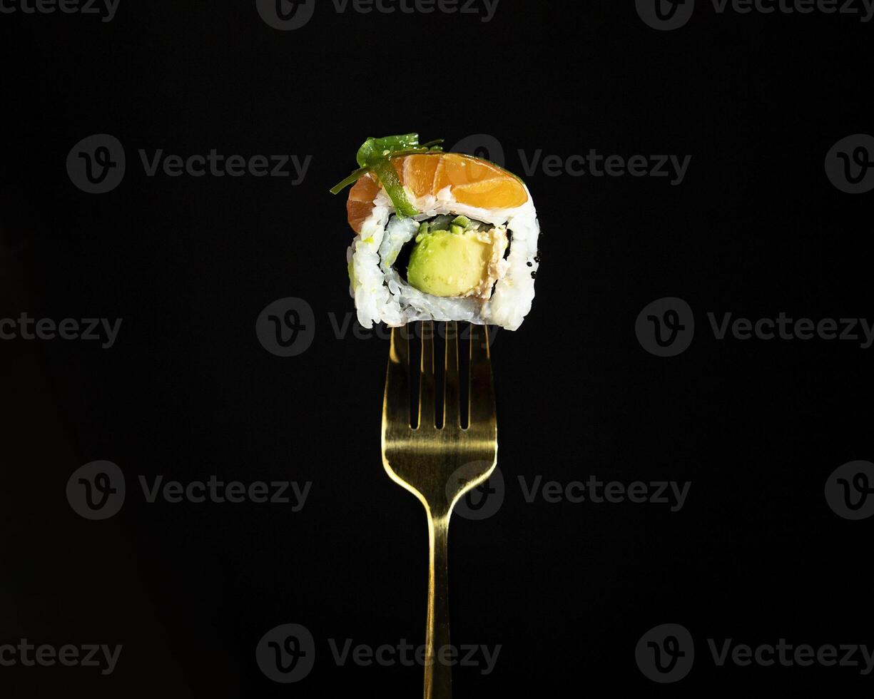 Japanese salmon sushi on a fork on the dark background photo