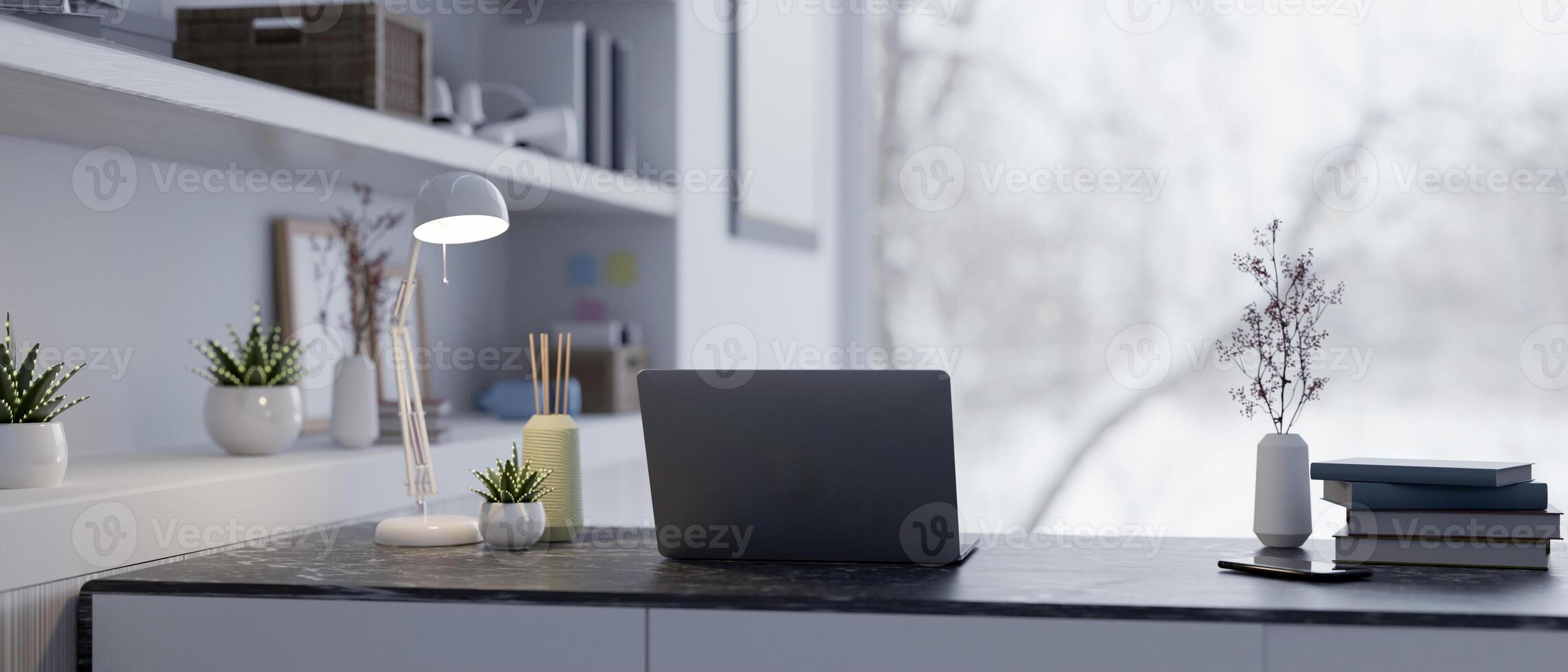 A back view of a laptop, a table lamp, and decor on a table in a modern home office workspace. photo