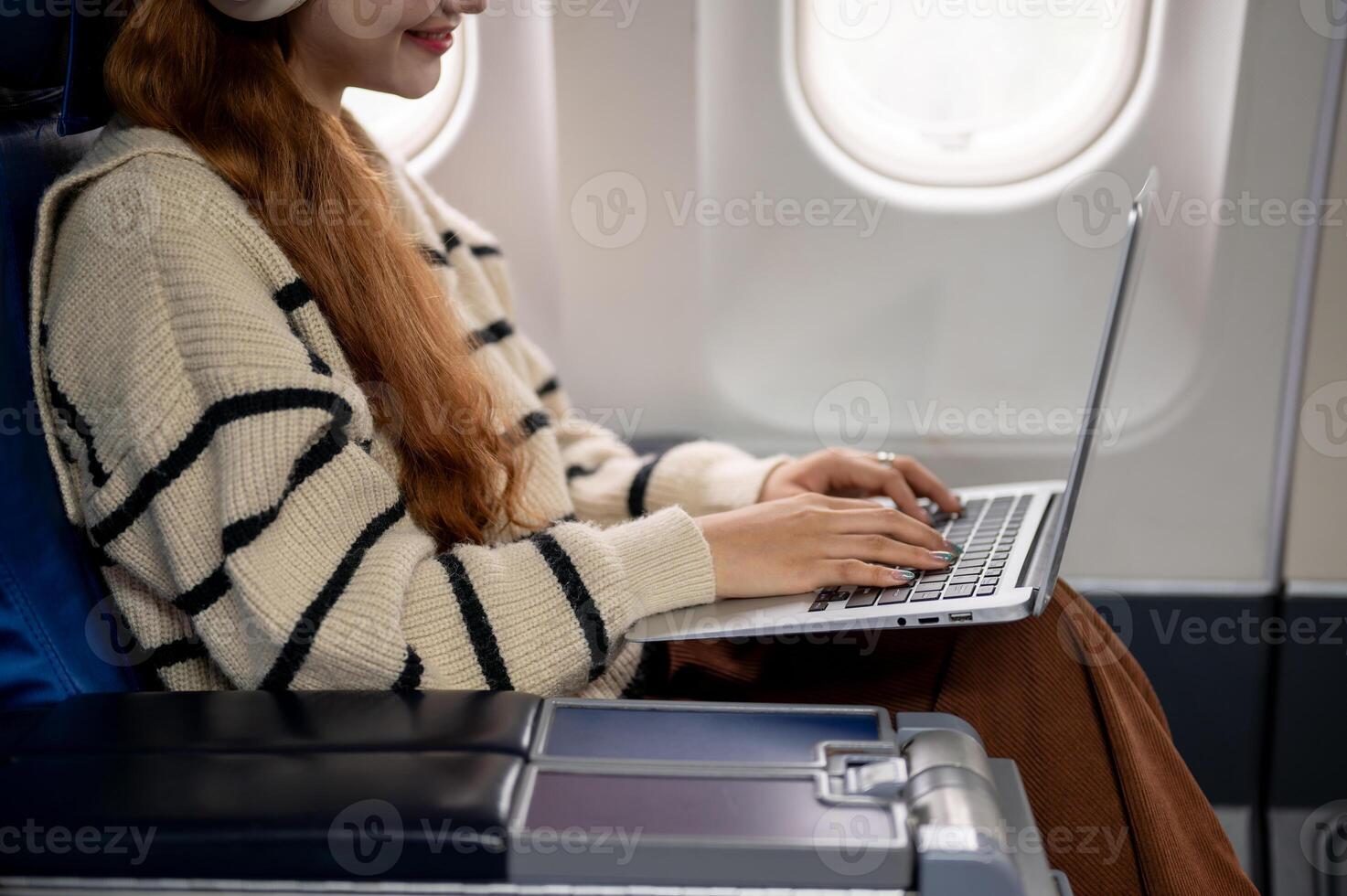 A close-up of a woman working on her laptop and typing on the keyboard during the flight. photo