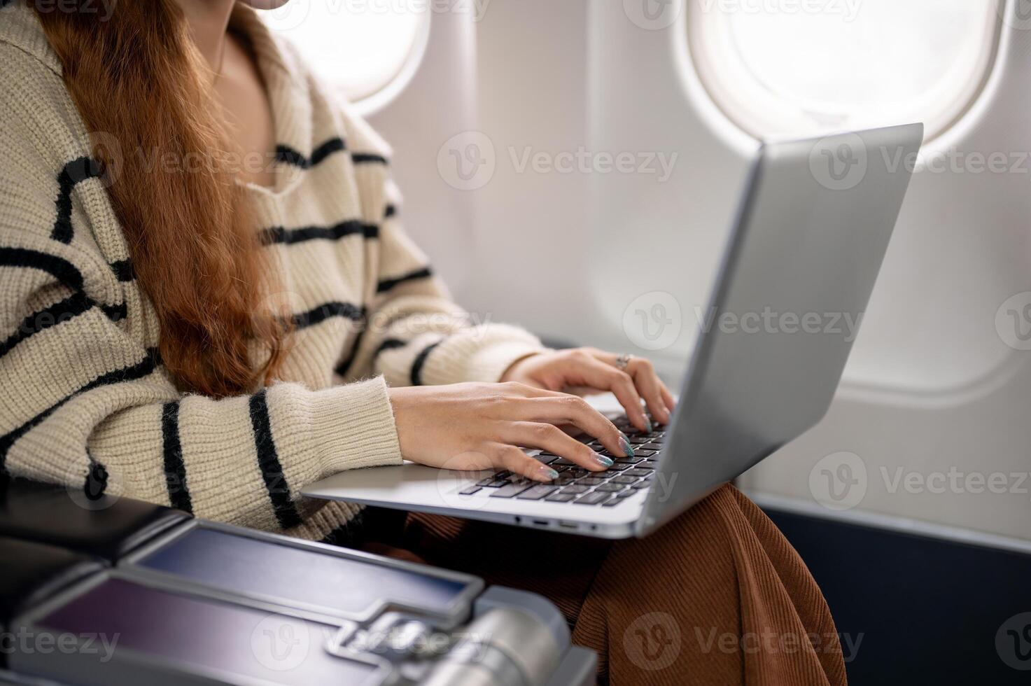 A close-up of a woman working on her laptop and typing on the keyboard during the flight. photo