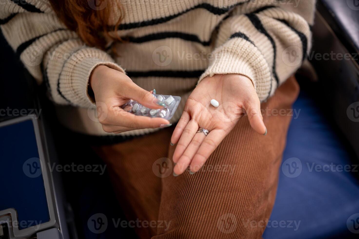 A close-up of a woman taking an airsick pill at her seat before the flight takes off. photo