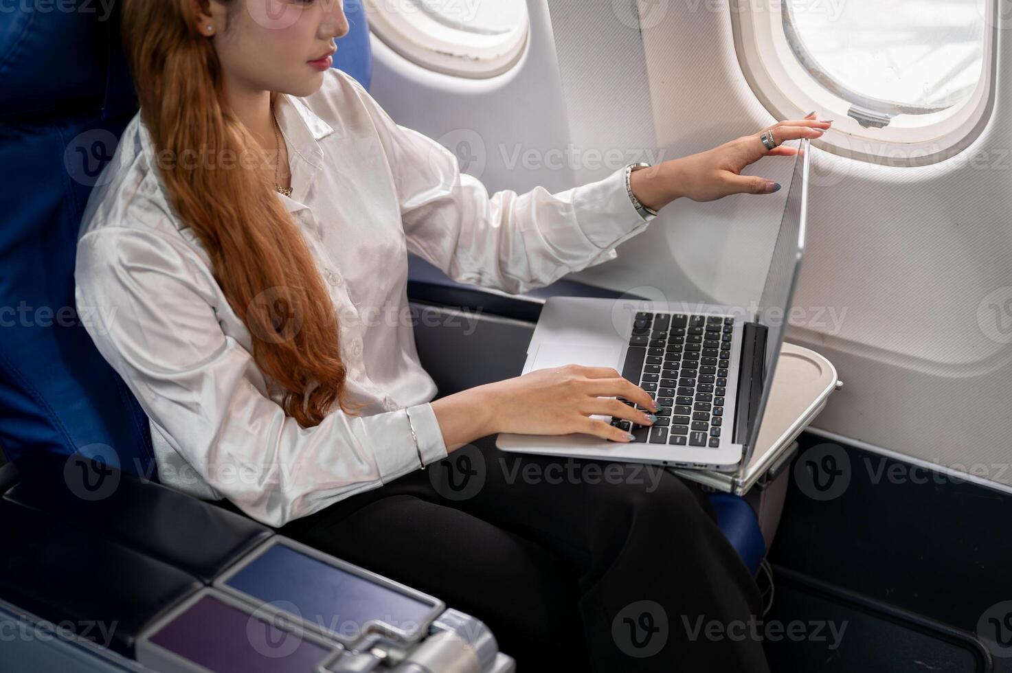 A close-up of a businesswoman typing on the laptop keyboard, working during the flight. photo
