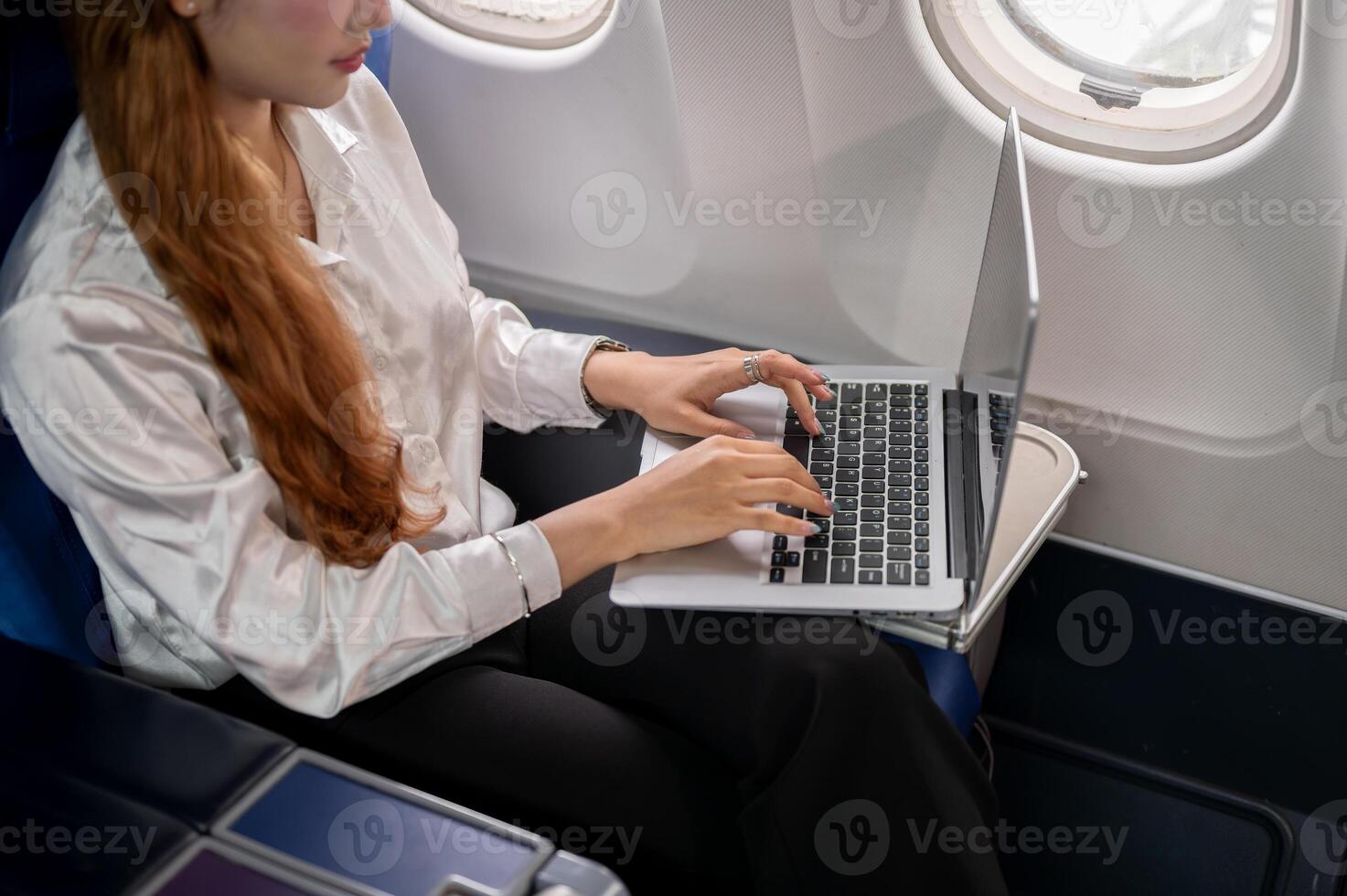 A close-up of a businesswoman typing on the laptop keyboard, working during the flight. photo
