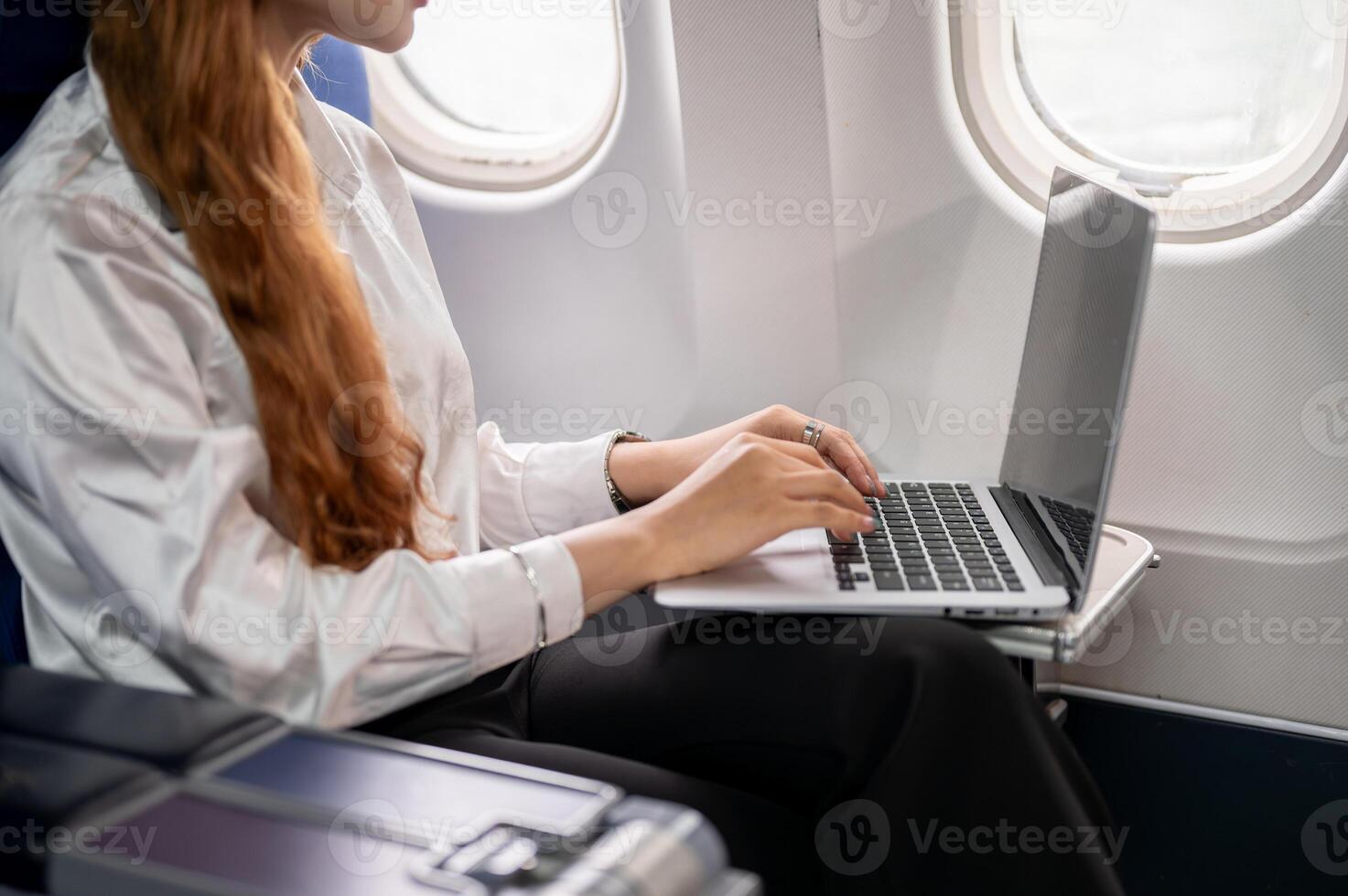 A close-up of a businesswoman typing on the laptop keyboard, working during the flight. photo
