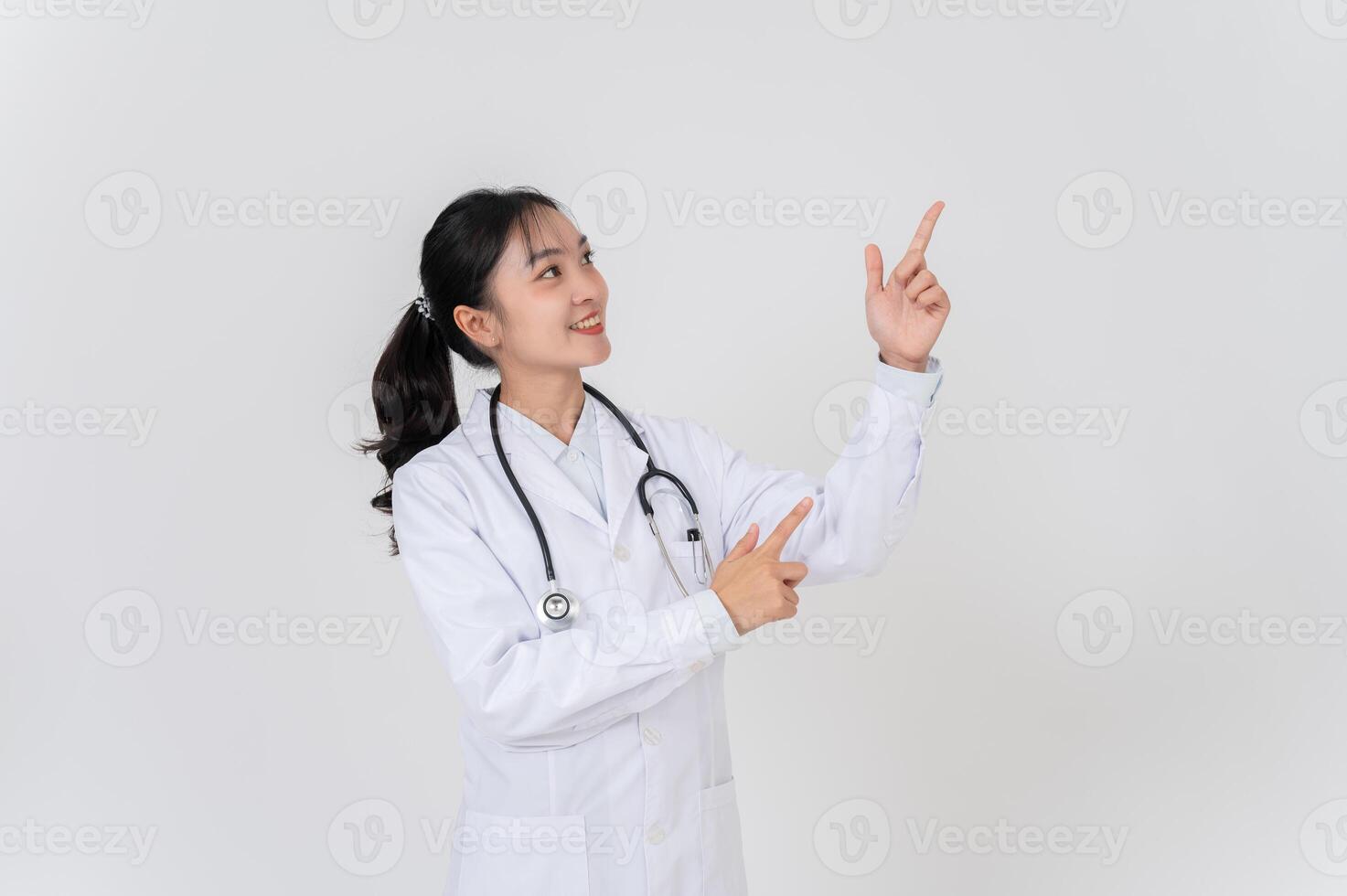A doctor in uniform smiling and pointing at an empty space, as if she is recommending something. photo