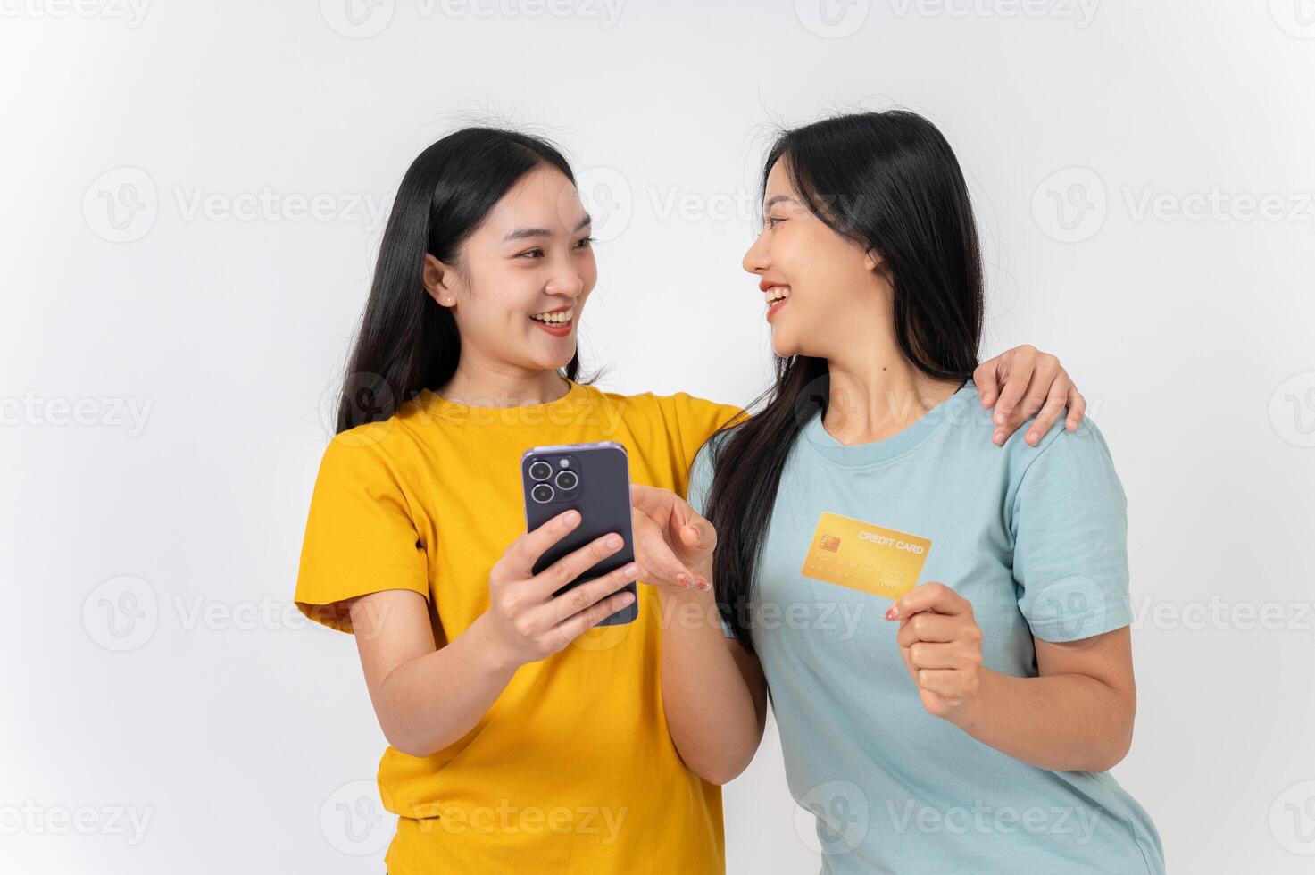 Two happy female friends holding a smartphone and a credit card, enjoying online shopping together. photo