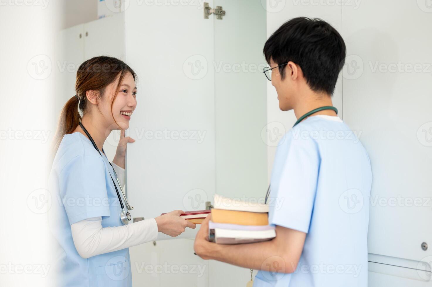 Two Asian male and female medical students are talking while getting their textbooks from a locker. photo