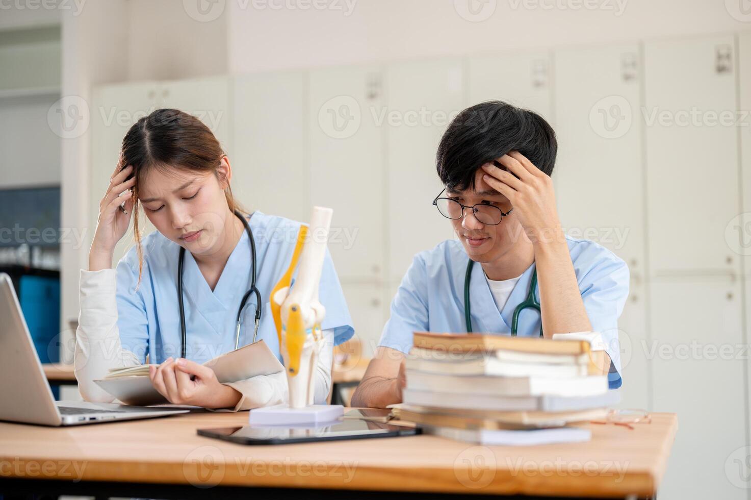 Two stressed and concerned Asian medical students are focused on working together in the library. photo