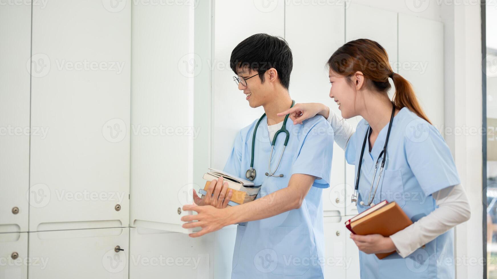 Two Asian male and female medical students are talking while getting their textbooks from a locker. photo