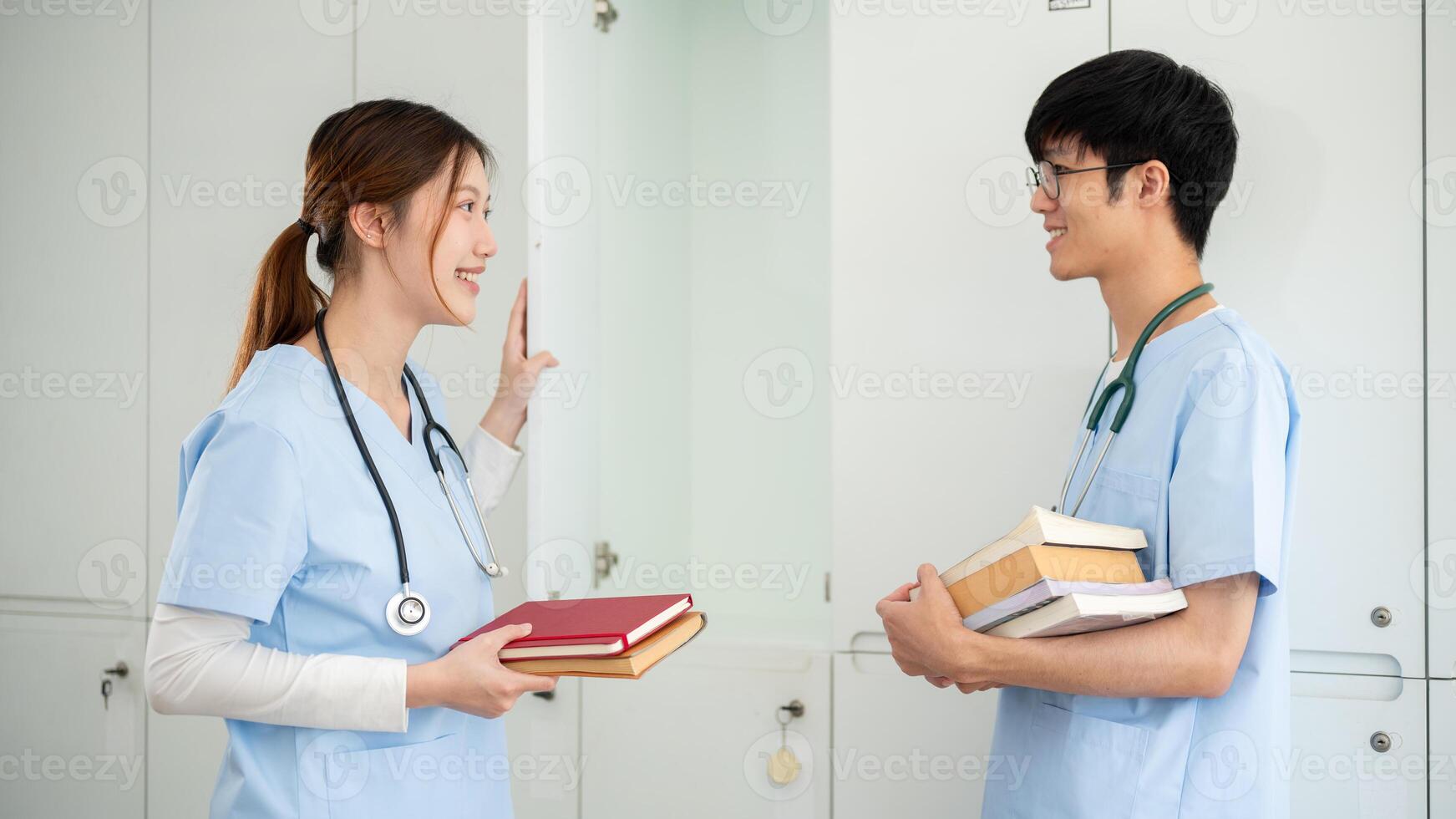Two Asian male and female medical students are talking while getting their textbooks from a locker. photo