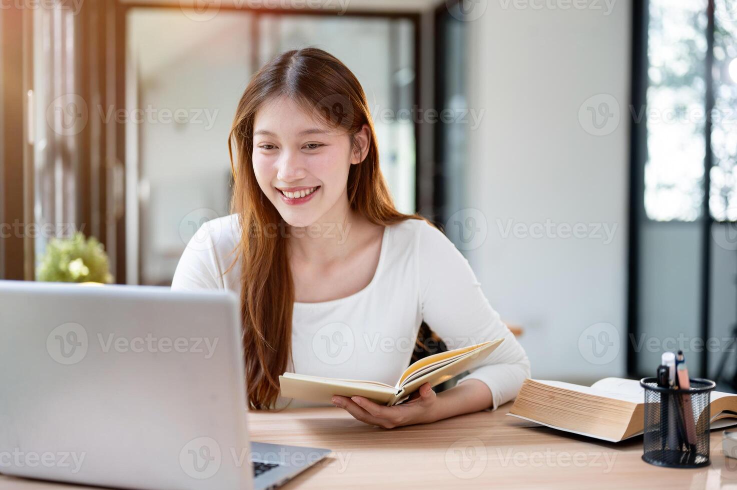 A beautiful Asian female college student working remotely from a cafe or studying in a library. photo