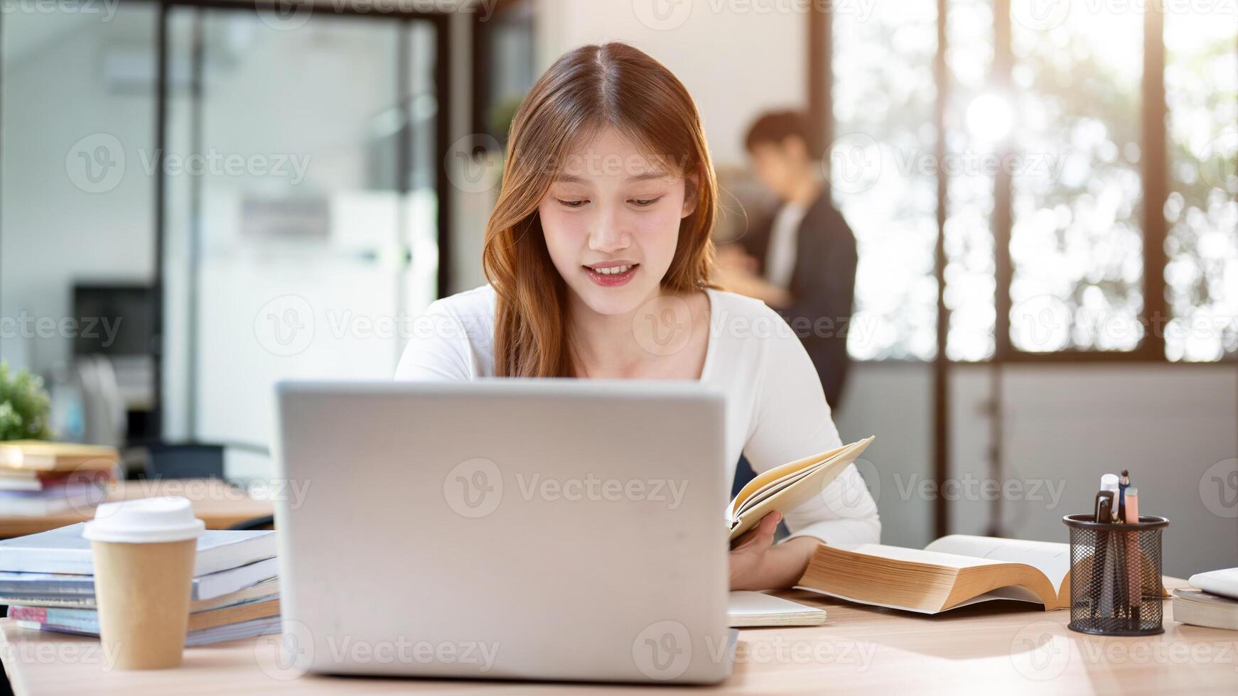 A beautiful Asian female college student working remotely from a cafe or studying in a library. photo