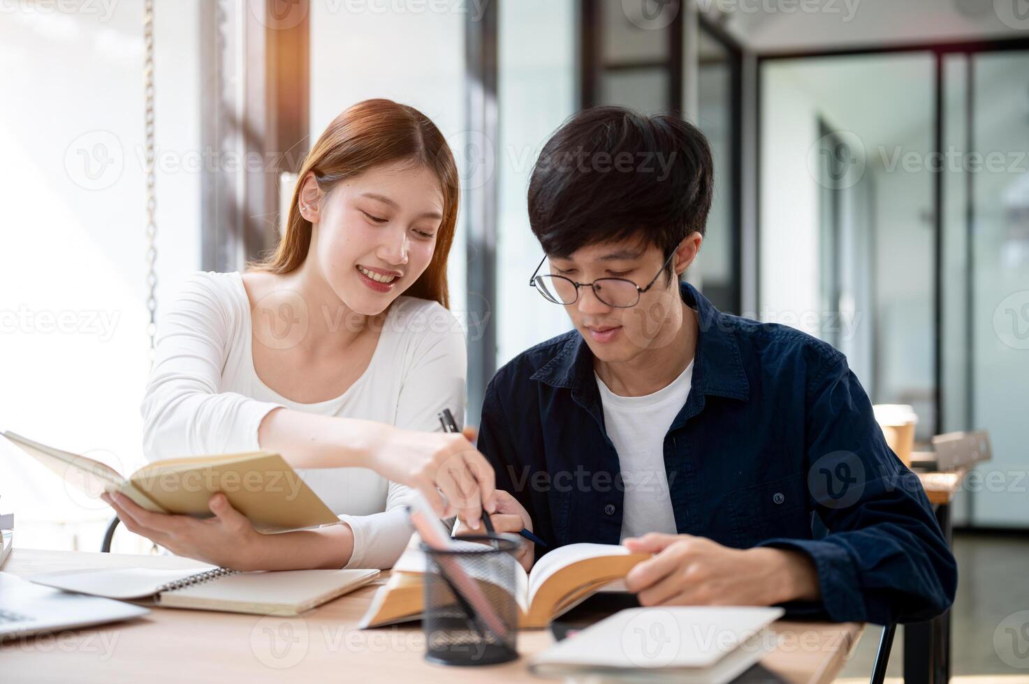 Two young Asian college students are studying and preparing for an exam together in a coffee shop. photo