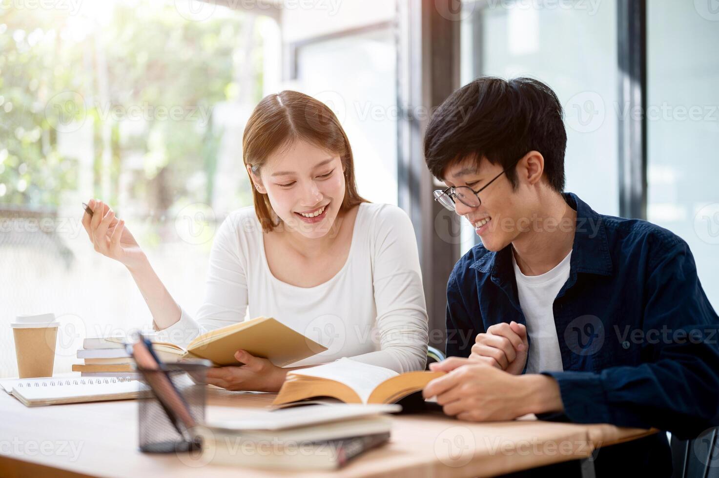Two young Asian college students are studying and preparing for an exam together in a coffee shop. photo