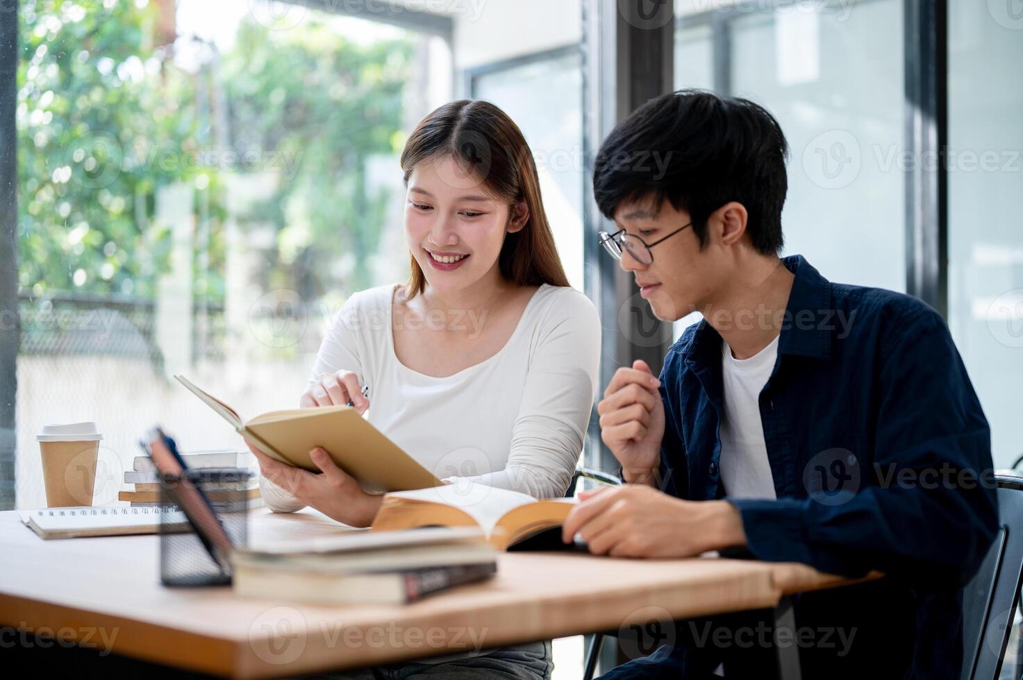 Two young Asian college students are studying and preparing for an exam together in a coffee shop. photo