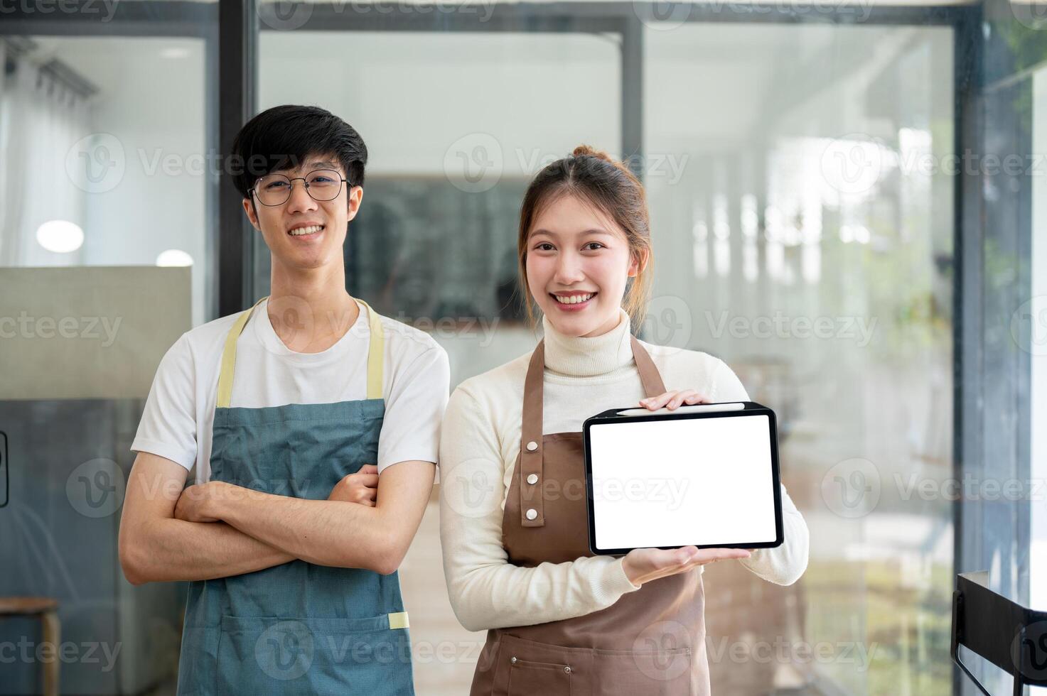Two smiling coffee shop baristas or staff members are showing a digital tablet to the camera. photo
