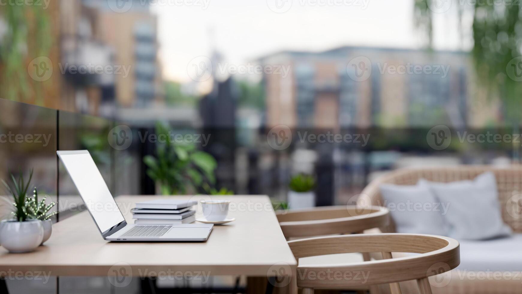 A close-up of a laptop on a wooden table with armchairs on a balcony of an apartment in the city. photo